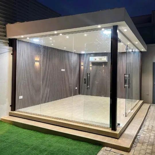 تنفيذ غرفة زجاجية خارجية وجلسة مجلس قزاز في حوش بجدة - تصميم بديل خشب رمادي مع سقف جبس وسبوتات ليد وابواب زجاج سحاب ومكيف